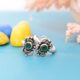 A pair of silver toe rings with green cutstones set in a floral design.