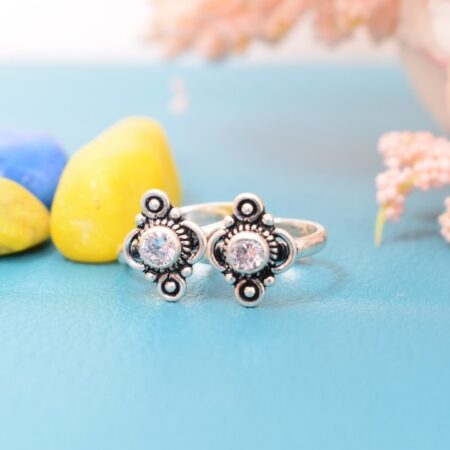 A pair of silver toe rings with white stones set in a geometric design.