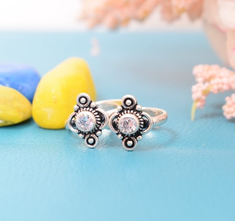 A pair of silver toe rings with white stones set in a geometric design.