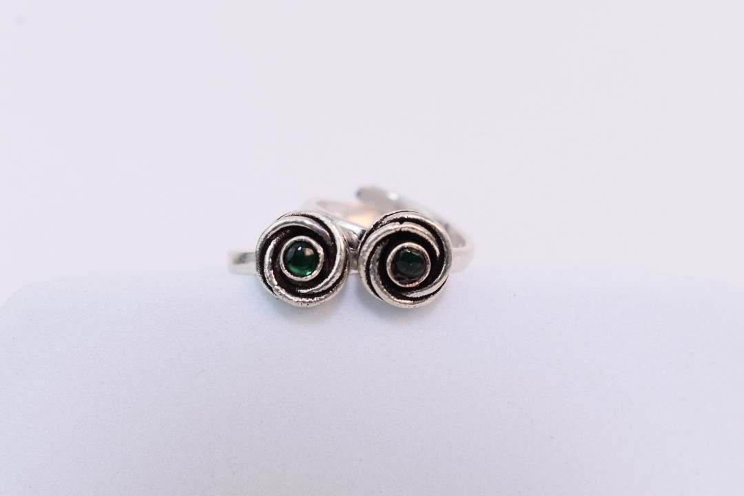 A pair of silver toe rings with green stones set in a spiral design