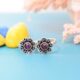 A pair of silver toe rings with purple stones set in a floral design.