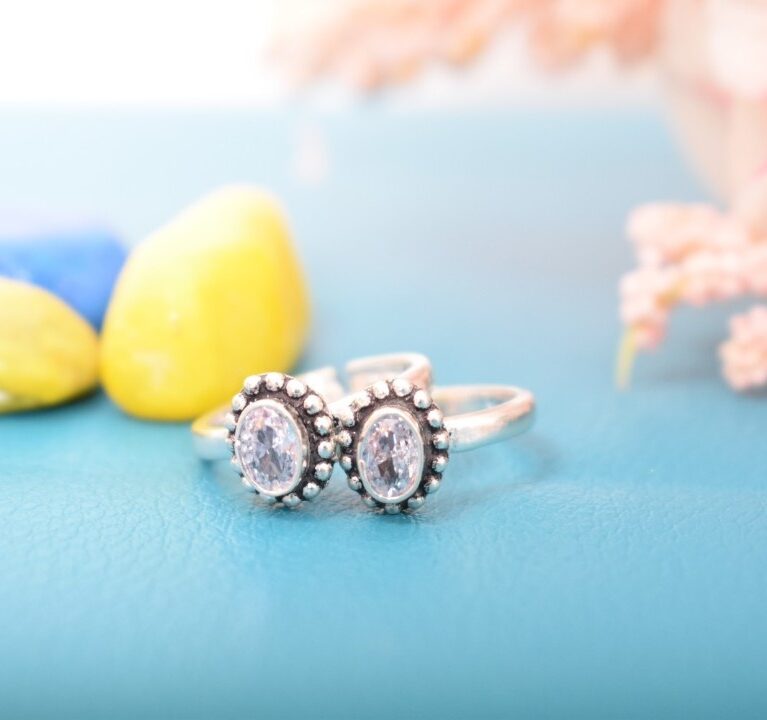A pair of silver toe rings with white stones set in an oval design.