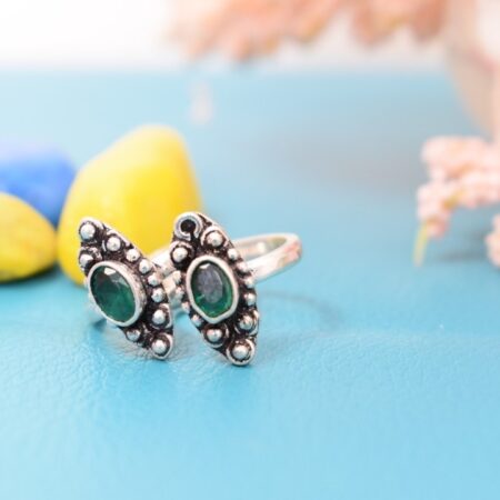 A pair of silver toe rings with green stones set in a marquise shape.