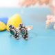 A pair of silver toe rings with green stones set in a marquise shape.