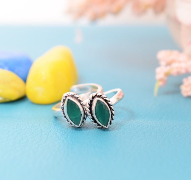 A pair of silver toe rings with green stones set in an oval design.