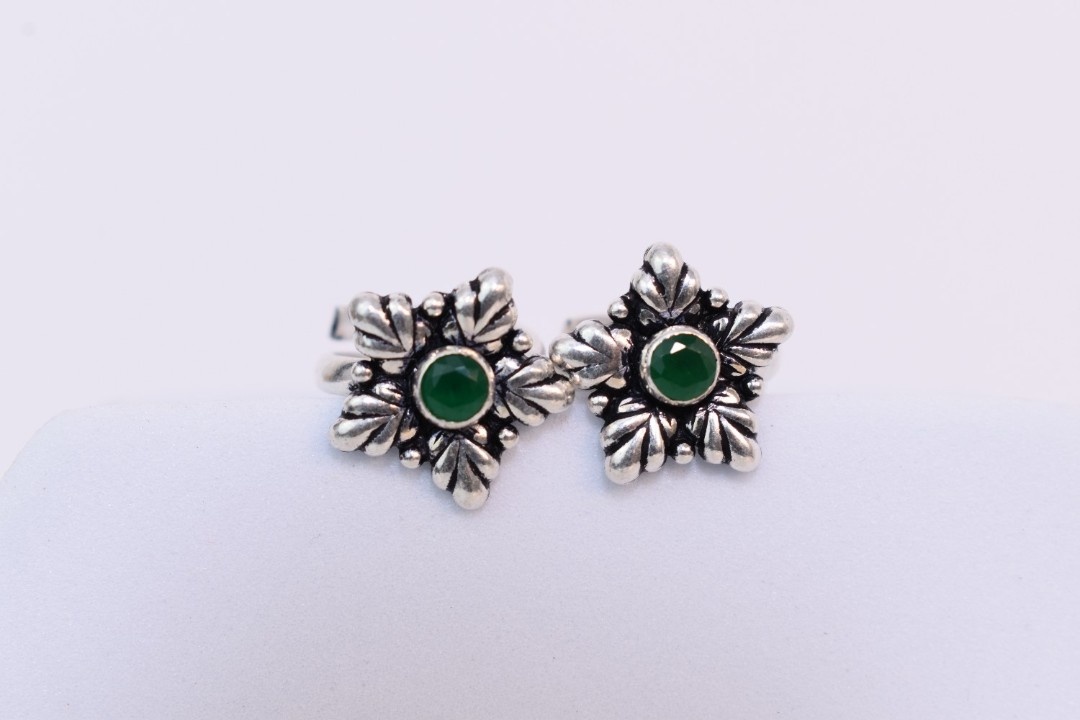 A pair of silver toe rings with green cutstones set in a star-shaped design.