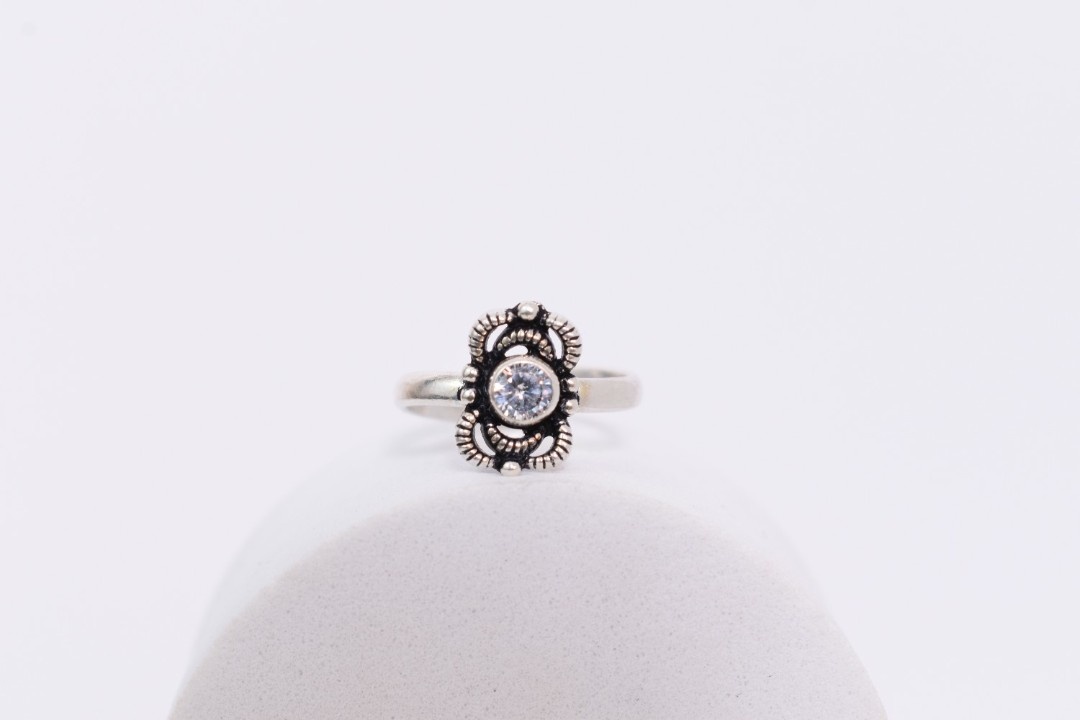 A pair of silver toe rings with white stones set in a floral design.