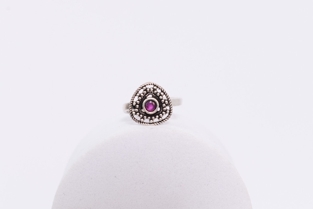 A pair of silver toe rings with purple stones set in a heart-shaped design.