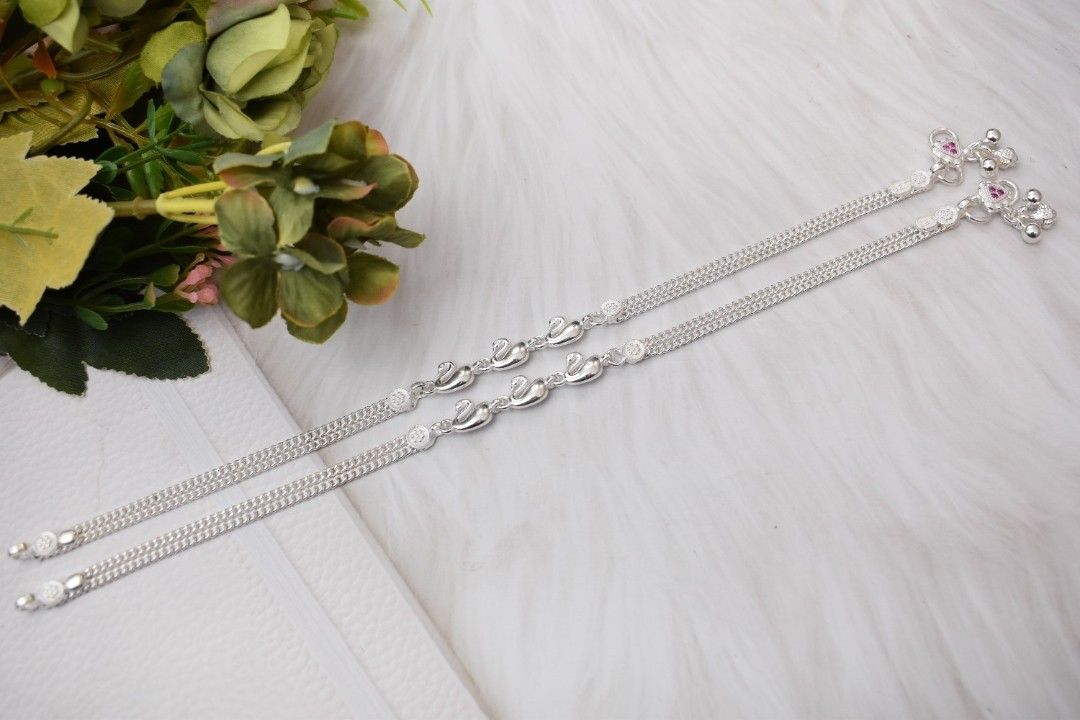 A pair of silver anklets with swan-shaped pendants.