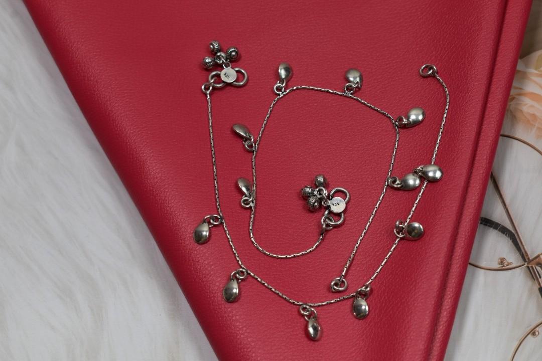 A pair of silver anklets with multiple teardrop-shaped pendants.