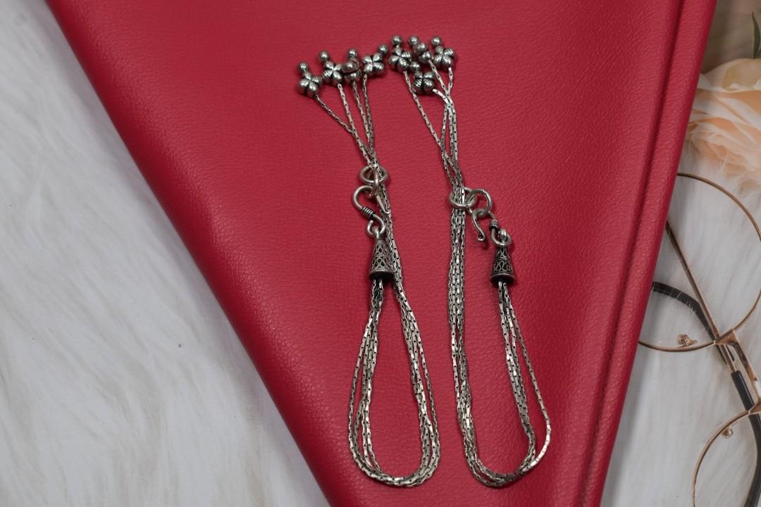 A silver anklet set with multiple chains and tassels.
