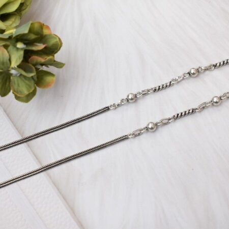 A pair of silver anklets with twisted chains and spherical beads.