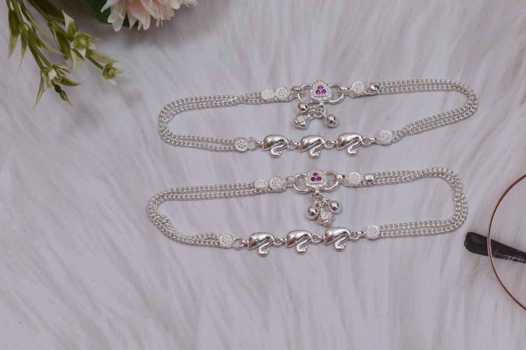 A pair of silver anklets with swan-shaped pendants.