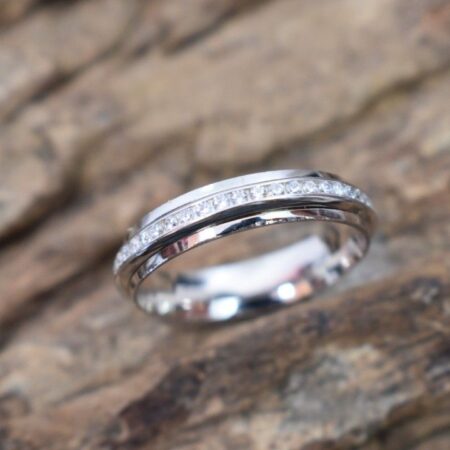 A silver ring with a band featuring a row of small CZs and a textured design.