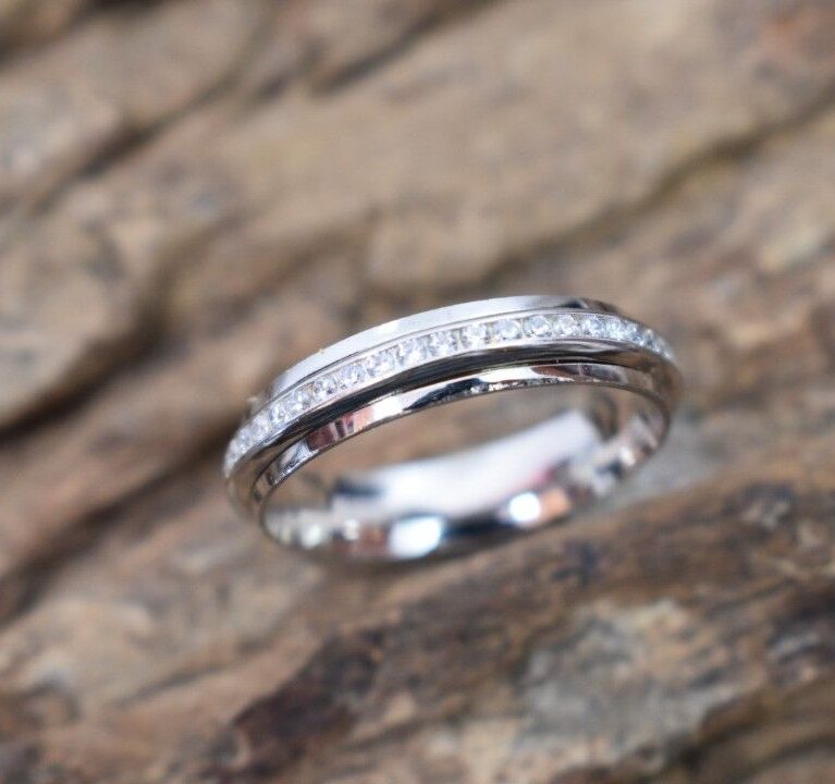 A silver ring with a band featuring a row of small CZs and a textured design.