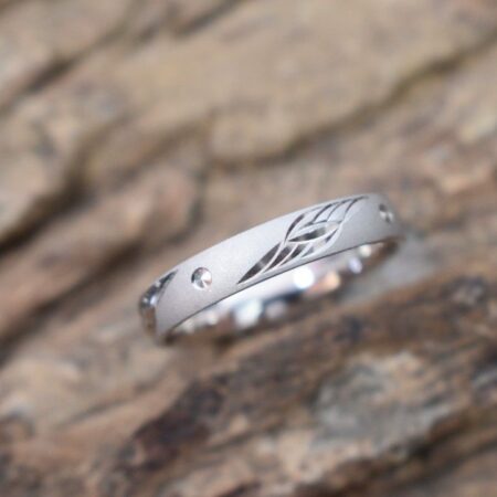 A silver ring with a delicate leaf design engraved on the band.