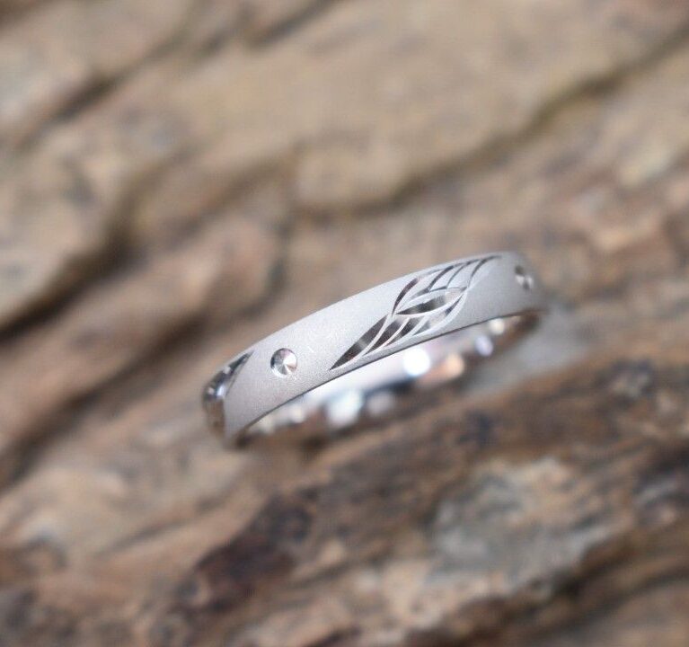 A silver ring with a delicate leaf design engraved on the band.