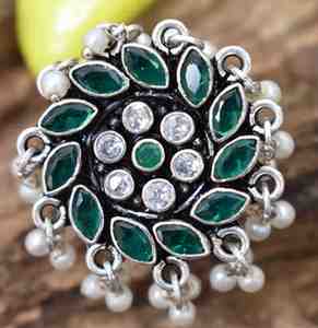 A silver ring with a circular design featuring green and white cutstones, adorned with pearls.