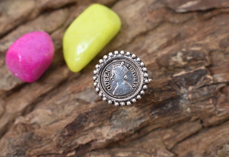 A vintage silver ring featuring a Queen Victoria coin set in a circular design with beaded edges.