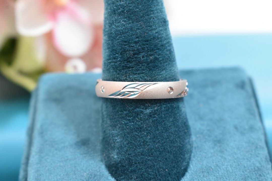 A silver ring with a delicate leaf design engraved on the band.
