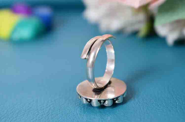 A silver ring with a circular design featuring a black cutstone surrounded by white cutstones.