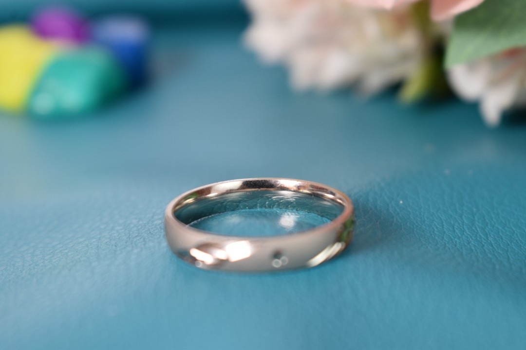 A silver ring with a delicate leaf design engraved on the band.