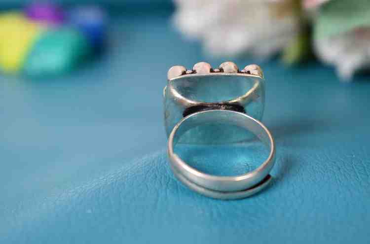 A silver ring with a square-shaped red cutstone surrounded by white cutstones.