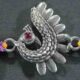 A silver Rakhi featuring a vibrant peacock design.