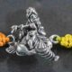 A silver Rakhi featuring a divine depiction of Lord Krishna with Gau Mata (cow).