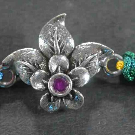 A delicate silver Rakhi with a fusion of leaf and floral designs