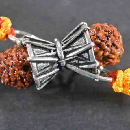 A silver Rakhi featuring Lord Shiva's Damru and Rudraksha beads.
