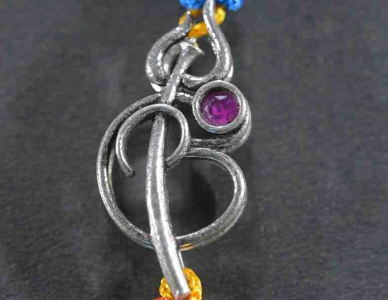 A silver Rakhi featuring a divine Om symbol intertwined with a Trishul (trident).